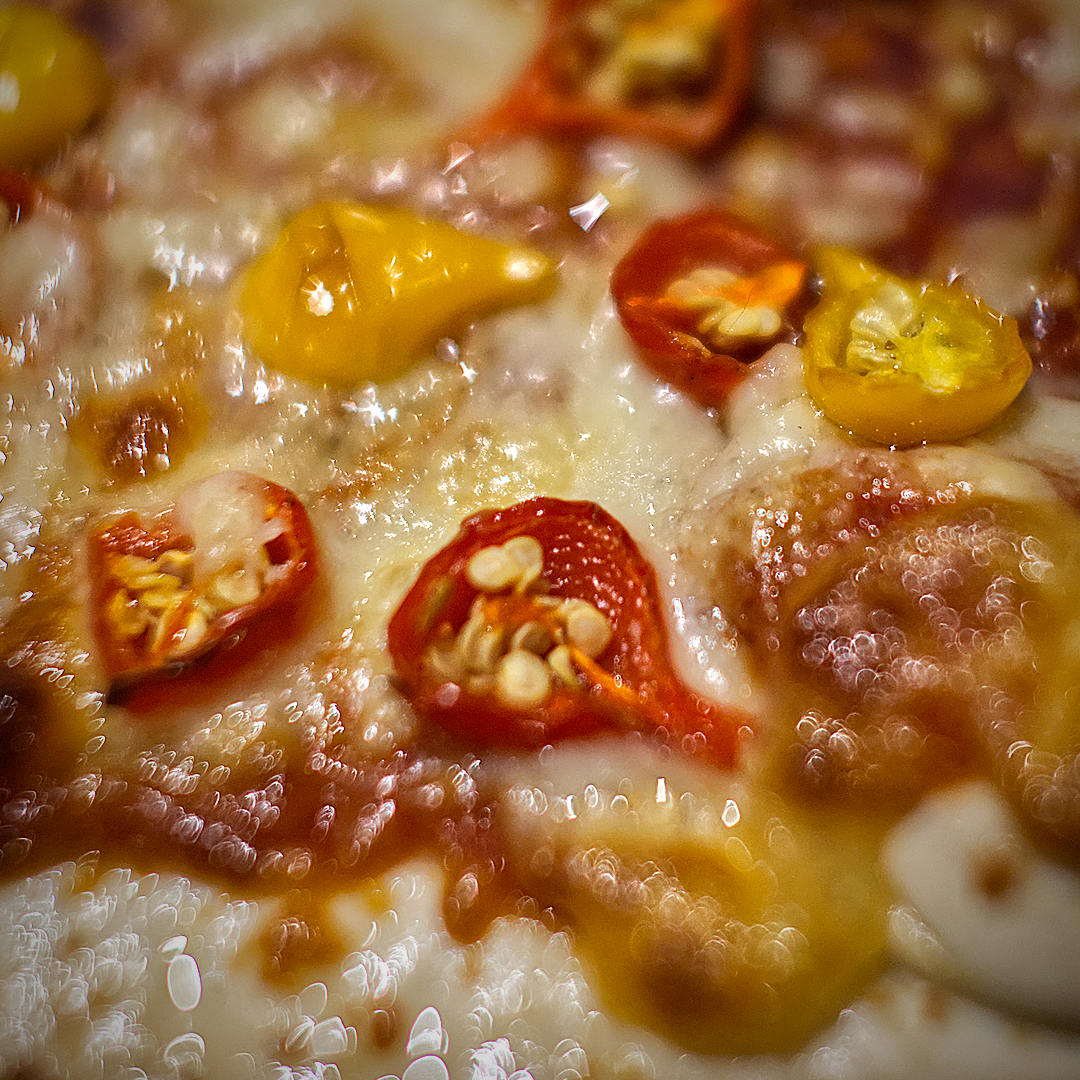  1. World of Chillies: Close-up of colourful red and yellow Biquinho chillies nestled in melted cheese on a pizza. 