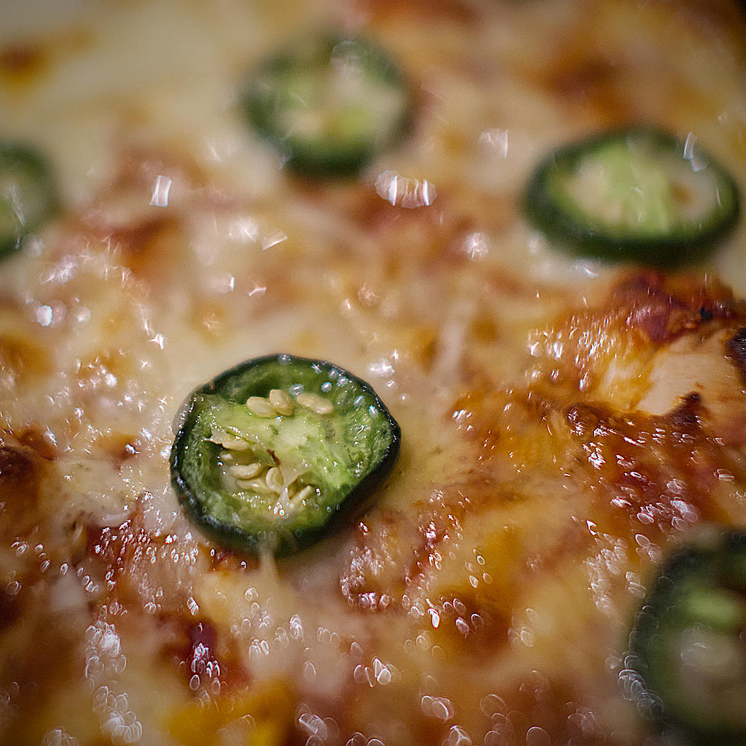  1. World of Chillies: Close-up of a freshly baked cheese pizza topped with green jalapeño slices. 