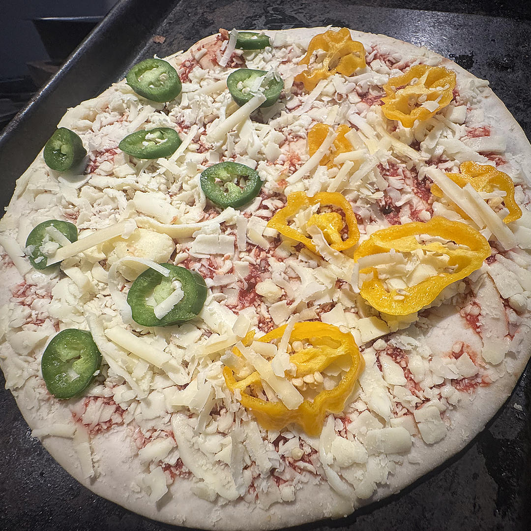  World of Chillies: Homemade pizza topped with sliced green jalapeños, yellow chillies and grated cheese before baking. 