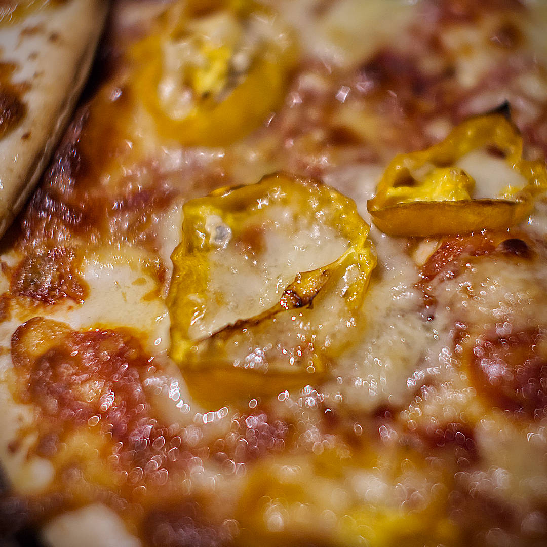  1. World of Chillies: Close-up of yellow Jamaican Hot chilli slices softened and roasted on a freshly baked pizza. 