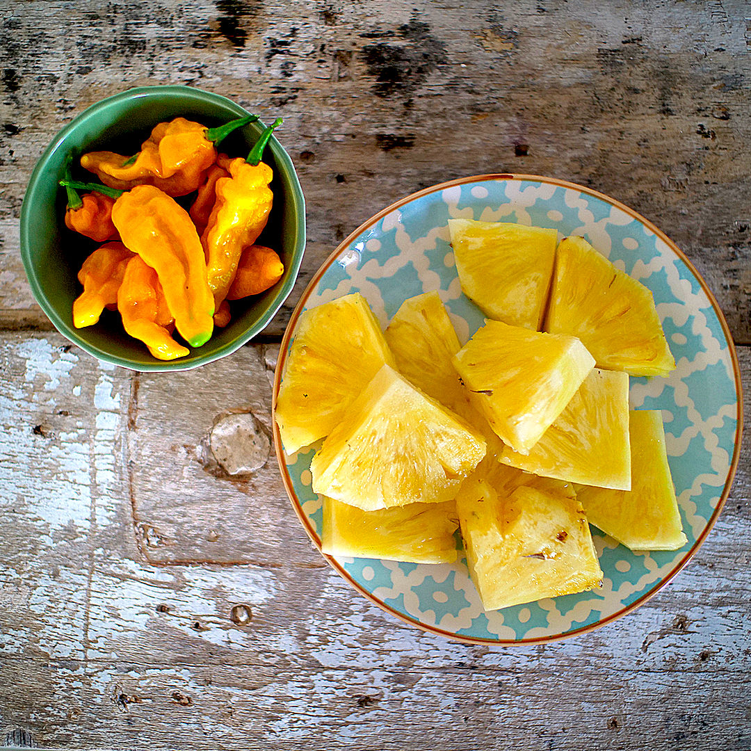 World of Chillies Fatalii chillies and fresh pineapple slices on rustic table
